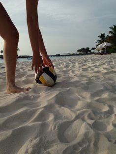 a person standing on top of a sandy beach next to a ball in the sand