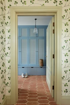 an open door leading to a bathroom with blue cabinets and wallpaper on the walls