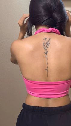 the back of a woman's neck with a flower tattoo on her lower back