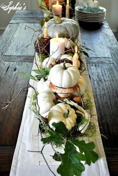 a long table with candles and pumpkins on it