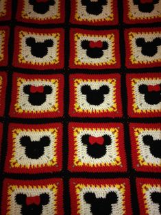 a crocheted blanket with mickey mouse heads on the squares in red, white and yellow