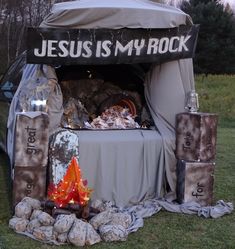 a tent set up in the grass with rocks around it and an open fire pit