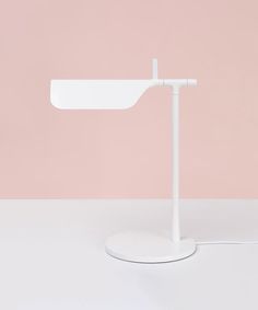 a white desk lamp with a pink wall in the background