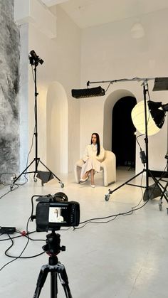 a woman sitting on a chair in front of a camera set up for a photo shoot