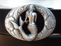 a belt buckle with a mermaid sitting on top of it