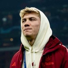 a young man wearing a hoodie looks off into the distance while standing in front of an empty stadium