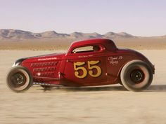 an old red race car driving in the desert