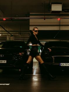 a woman riding a bike through a parking garage next to two parked cars in front of her