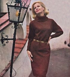 a woman standing next to a lamp post wearing a brown dress and high heeled boots