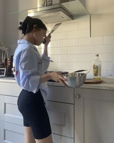 a woman is standing in the kitchen cooking