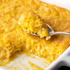 a casserole dish with corn and a spoon resting on it's side