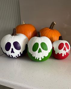 three pumpkins with painted skulls on them are sitting on a counter next to each other