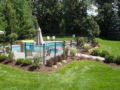 a pool surrounded by lush green grass and trees