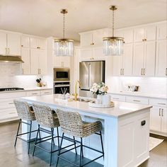 a large kitchen with white cabinets and an island in the middle is surrounded by four bar stools