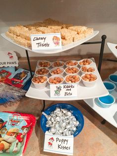 there are many different foods on the shelves in this buffet table, including rice krispy kreme and candy treats