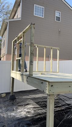 a man standing on top of a wooden deck next to a building with a white fence