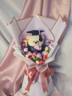 a teddy bear in a graduation cap and flowers