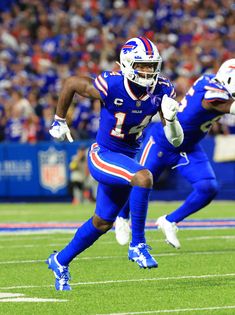 a football player running with the ball in his hand and other players on the field behind him