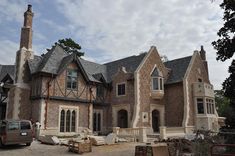 a large brick house being built on the side of a road with a truck parked in front of it