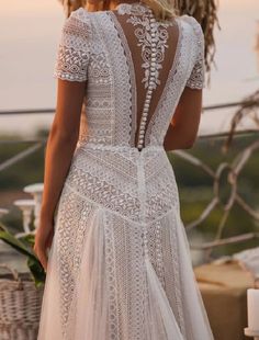 a woman wearing a white wedding dress with an open back and lace detailing on it