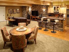 a living room filled with furniture next to a kitchen and dining room table in front of a stone wall