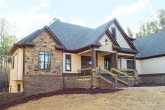 a brick house with stone steps and brown shingles on the front porch is surrounded by trees