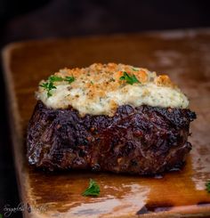 a piece of steak with mashed potatoes and parmesan cheese on the top