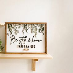 a wooden shelf with a framed sign on top of it that says be still and know that i am god