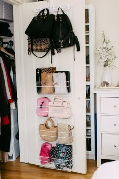 a closet with several baskets and purses hanging on the wall next to a bed