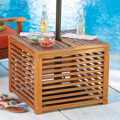 an outdoor table next to a pool with drinks on it and two chairs around it