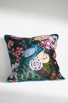 a decorative pillow on a white couch with flowers and a bird in the middle,