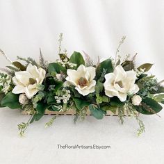 flowers and greenery are arranged in a wooden box