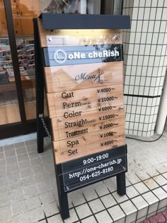 a wooden sign sitting on the side of a sidewalk next to a store front window