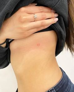 a woman with a small heart tattoo on her stomach