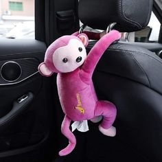 a pink stuffed monkey hanging from the side of a car seat with its arms in the air