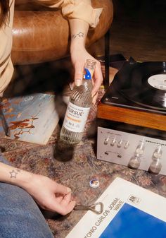 a person sitting on the floor next to a record player and a bottle of alcohol