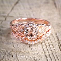 two wedding bands with an oval morganite in the center on a piece of wood