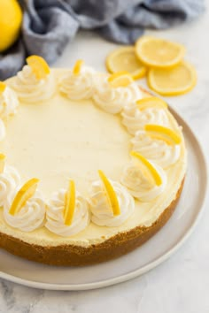 a white plate topped with a cheesecake covered in icing and sliced lemons