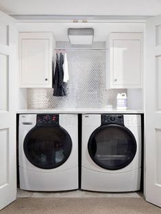 a washer and dryer in a small room with white cabinets on the wall