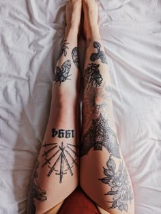 a woman with tattoos laying on top of a bed