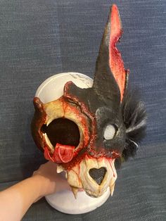 a person holding a fake animal mask with blood on it's face and mouth