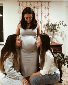 three pregnant women sitting on the floor with their baby bumps up to each other