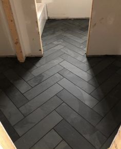 an open door leading to a bathroom with black tile