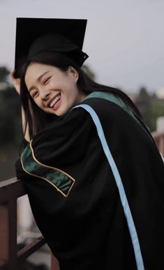 a woman wearing a graduation cap and gown posing for the camera with her arms around her neck