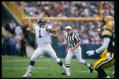 a football player is throwing the ball in front of an opposing player and referee during a game