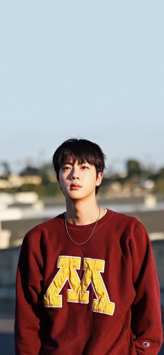 a young man wearing a maroon sweatshirt with yellow letters on it