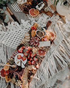 an assortment of food is laid out on a white tablecloth with tassels