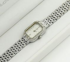 This silver-colored watch boasts a rectangular case surrounded by stones, adding a touch of elegance and sparkle. The grey metallic dial is also adorned with stones, enhancing its luxurious appeal. Paired with a classic metal bracelet, the watch strikes a balance between simplicity and brilliance. It's a sleek, bright, and elegant accessory that stands out for its understated glamour and sophistication. Dimensions: Bracelet Length: up to 16 cm (6.3 inches) - adjustable Case Width: 1.7 cm (0.4 inches) Case Height: 2.3 cm (0.9 inches) Bracelet Width: 1 cm (0.4 inches) Condition: The watch is in good condition, with minor wear on the bracelet and a tiny chip on the glass between the 3 and 4-hour marks, details in the photo. All presented watches are tested and in working condition, also equip Elegant Rectangular Diamond Watch Gift, Elegant Rectangular Diamond Watch As Gift, Elegant Rectangular Diamond Watch For Gift, Elegant Rectangular Diamond Watch For Anniversary, Elegant Stainless Steel Diamond Watch With Accents, Classic Rectangular Diamond Watch For Gift, Elegant Stainless Steel Diamond Watch With Diamond Accents, Rectangular Silver Watch As A Gift, Elegant Rectangular Diamond Watch With Metal Dial