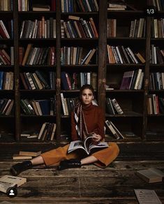 a woman sitting on the floor in front of a bookshelf filled with books