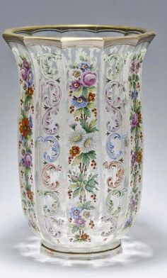 an ornate vase with flowers and leaves painted on the side, sitting on a white surface